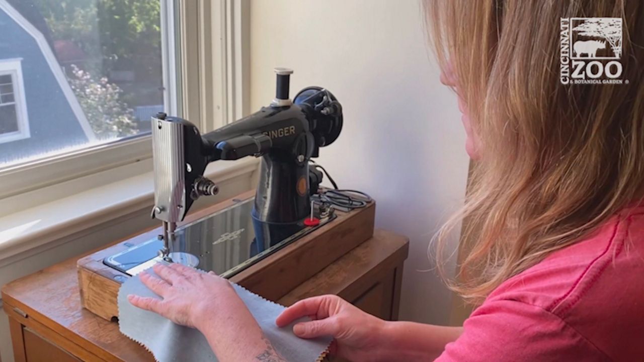 woman in pink shirt sewing on a black sewing machine