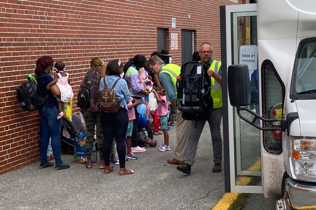 Some of the 191 asylum seekers from African countries housed temporarily at a basketball arena board buses and vans after the closing of the shelter at the gymnasium on Wednesday, Aug. 16, in Portland. (AP Photo/David Sharp)