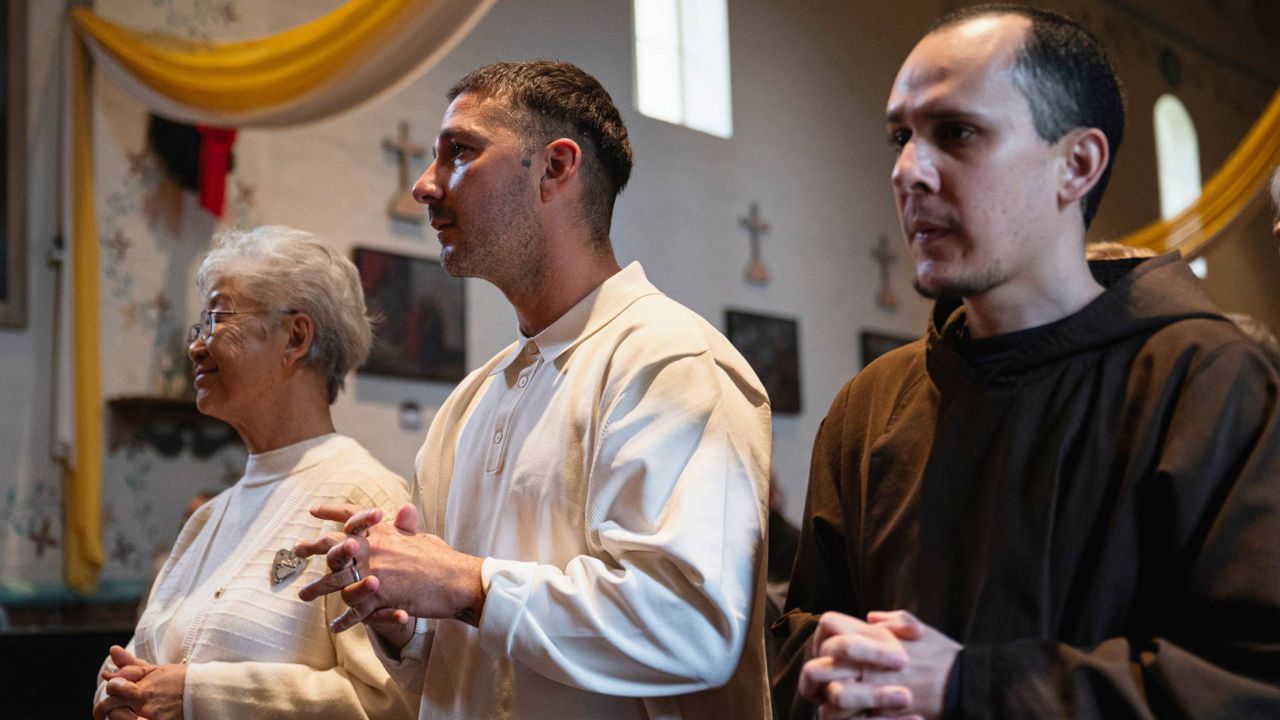 In this photo provided by Word on Fire Catholic Ministries, actor Shia LaBeouf, center, participates in his Catholic confirmation ceremony, accompanied by his confirmation sponsor, Capuchin friar Brother Alexander Rodriguez, right, at Old Mission Santa Inés Parish in Solvang, Calif., on Dec. 31, 2023. (Word on Fire Catholic Ministries via AP)