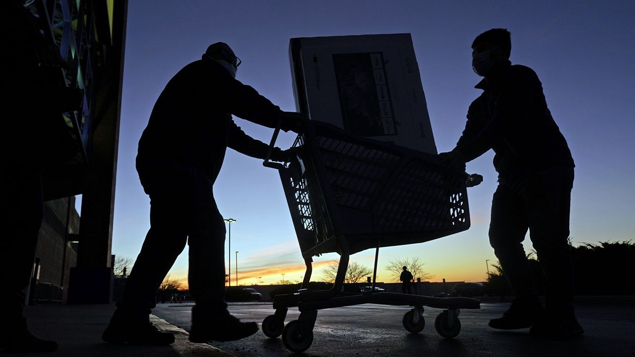 People transport a television to their car after shopping during a Black Friday sale at a Best Buy store on Friday, Nov. 26, 2021, in Overland Park, Kan. (AP Photo/Charlie Riedel, File)