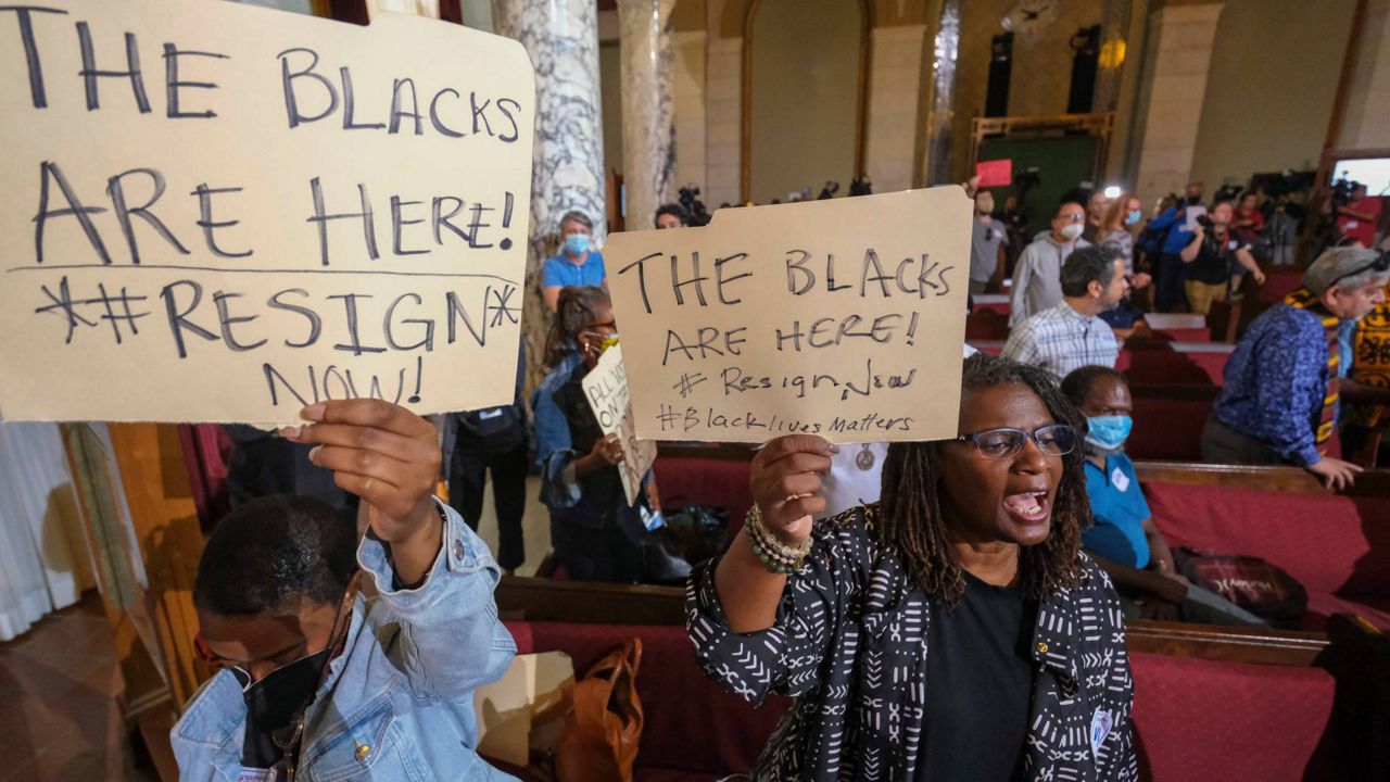 People hold signs and shout slogans before the starting of the Los Angeles City Council meeting on Tuesday in LA. (AP Photo/Ringo H.W. Chiu)