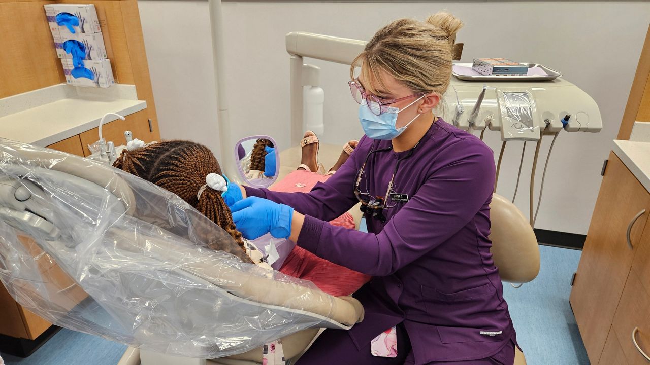Sinclair Community College dental hygiene student Hunter Class performs a dental exam on a refugee child.