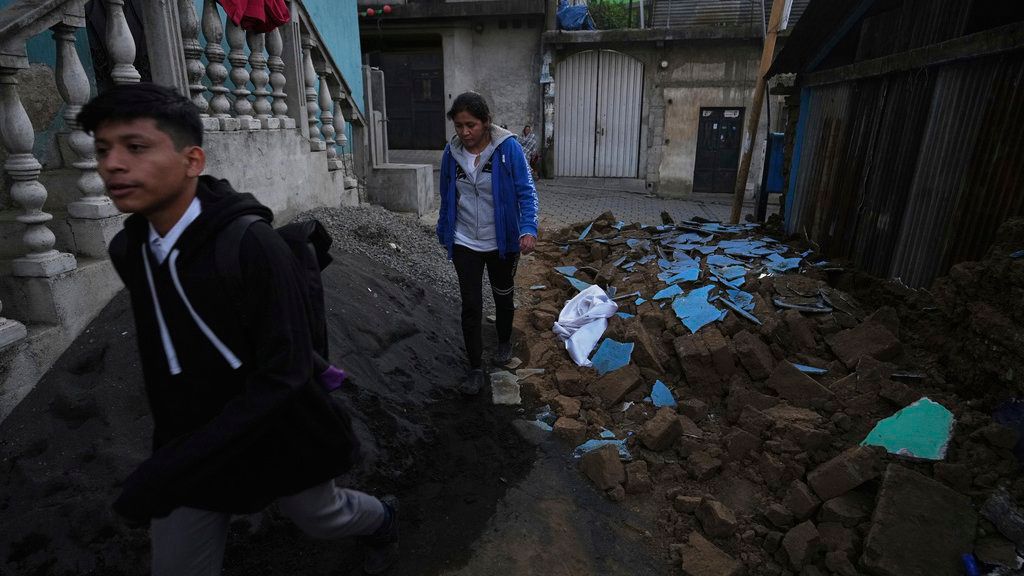 Vecinos caminan entre los escombros de una casa dañada en Palin, Guatemala, el miércoles 9 de julio de 2025, tras una serie de sismos.