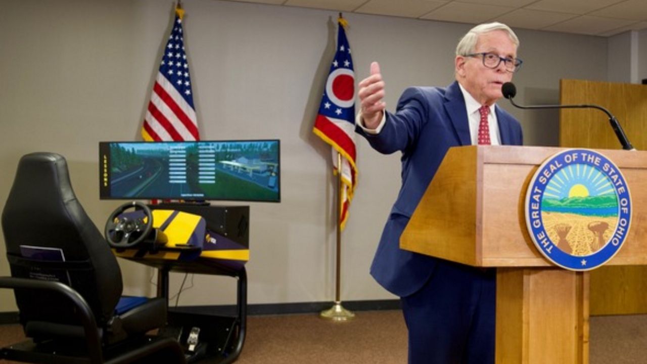 Ohio Gov. Mike DeWine speaks in front of a driving simulator.