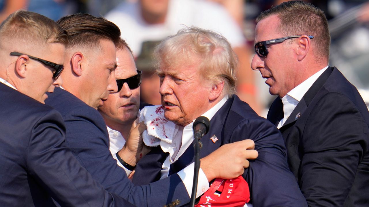 Republican presidential candidate former President Donald Trump is helped off the stage at a campaign event in Butler, Pa., on Saturday, July 13, 2024. (AP Photo/Gene J. Puskar)