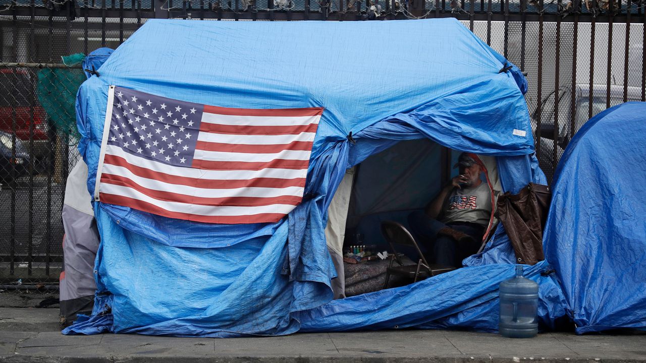 A man smokes inside a tent on skid row Friday, March 20, 2020, in Los Angeles.  (AP Photo/Marcio Jose Sanchez)