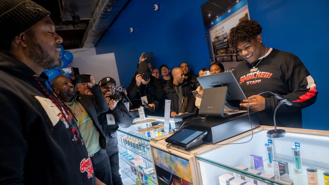 Roland Conner, left, browses his own stock before making the first legal purchase of cannabis, bought from his son, Darius, right, in the "pop up" location of their business Smacked, Tuesday, Jan. 24, 2023, in New York. The store is the first Conditional Adult-Use Retail Dispensary (CAURD) opening since the legalization of cannabis that is run by businesspeople who had been criminalized by cannabis prohibition. (AP Photo/John Minchillo)