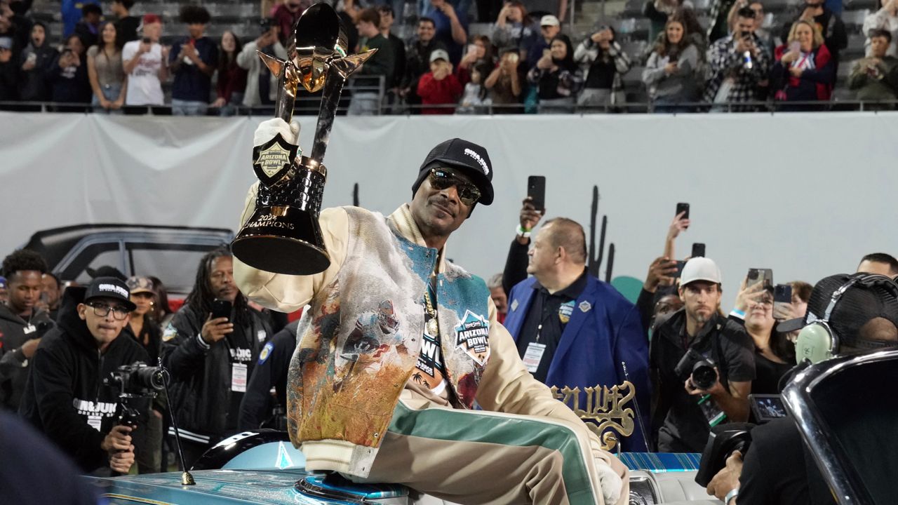 Rapper Snoop Dogg, center, arrives with the trophy after Miami (Ohio) defeated Colorado State in the Arizona Bowl NCAA college football game, Saturday, Dec. 28, 2024, in Tucson, Ariz.