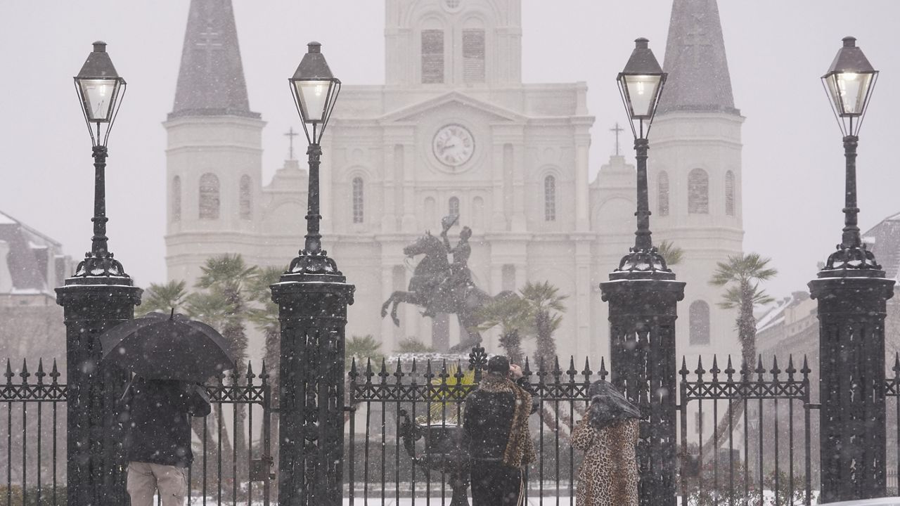 People stop to take pictures at Jackson Square as snow falls in New Orleans, Tuesday, Jan. 21, 2025. (AP Photo/Gerald Herbert)