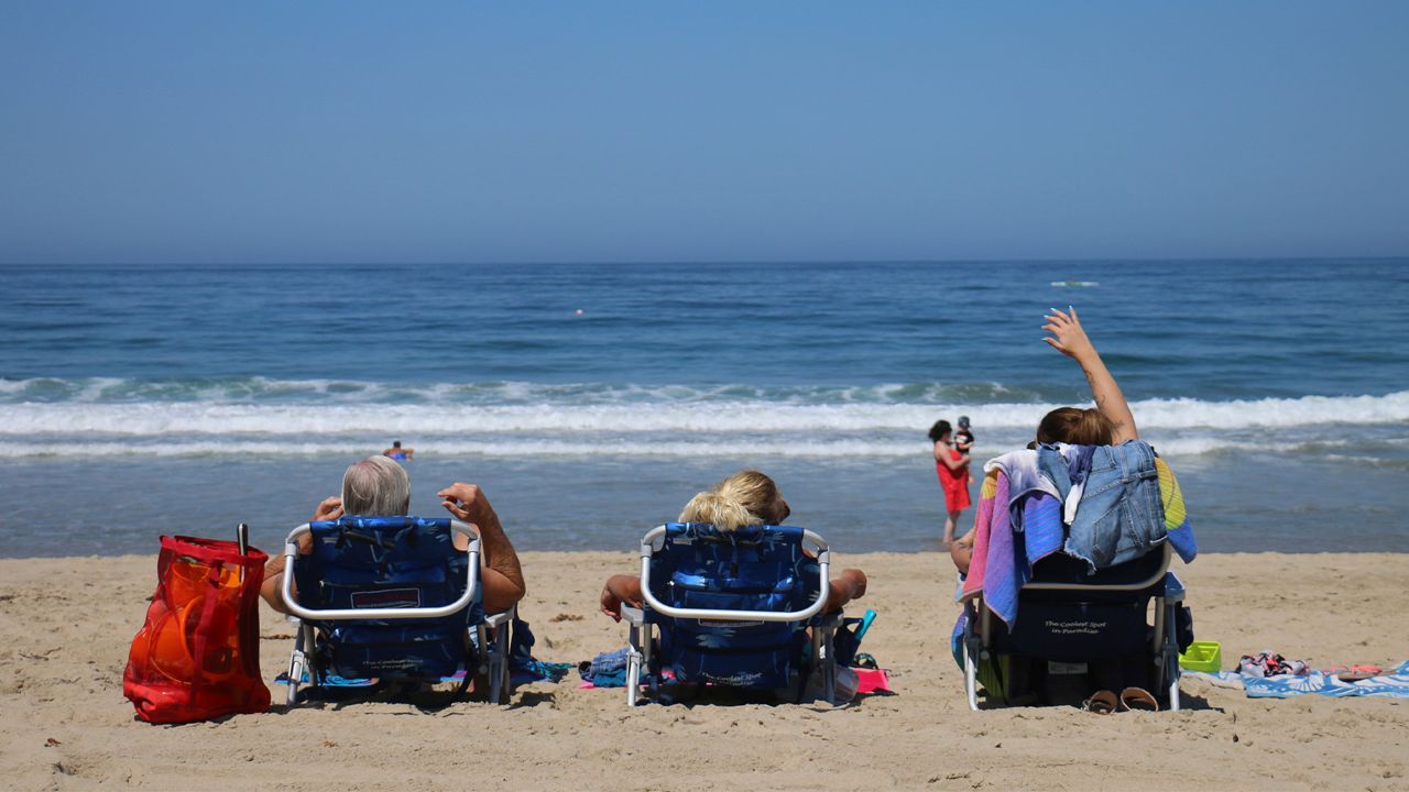 People watch the waves in Hermosa Beach, Calif., as a record-setting heat wave hit Southern California Friday, July 6, 2018. (AP Photo/Ariel Tu)