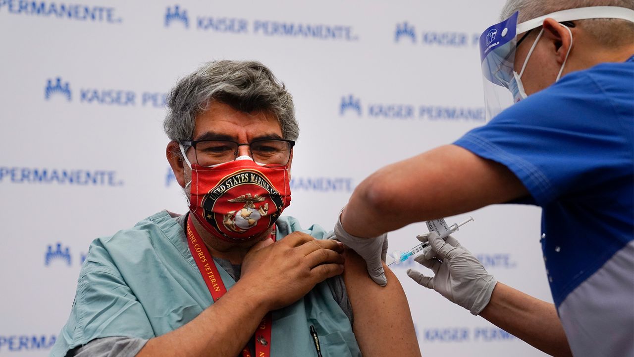 Respiratory care practitioner Raul Aguilar receives the Pfizer-BioNTech COVID-19 vaccine at Kaiser Permanente Los Angeles Medical Center in Los Angeles, Monday, Dec. 14, 2020. (AP Photo/Jae C. Hong)