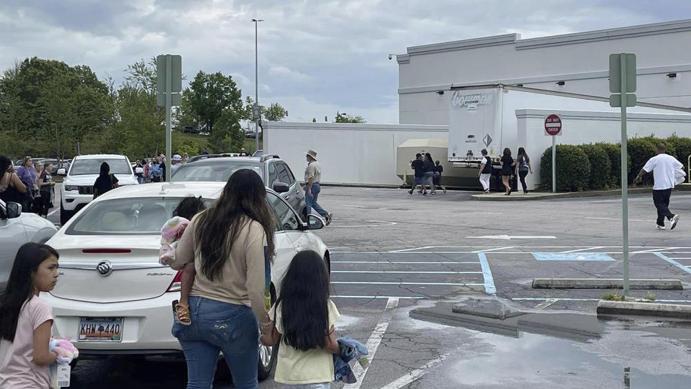 People walk through a parking lot at the Columbiana Centre mall in Columbia, S.C. on Saturday, April 16, 2022, as police investigate a shooting at the shopping center. (Justin Smith via AP)