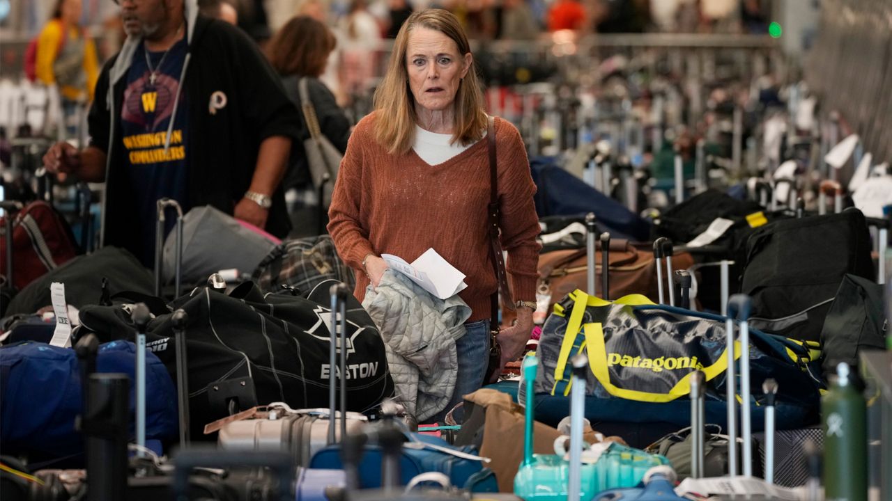 A traveler wades through the field of unclaimed bags at the Southwest Airlines luggage carousels at Denver International Airport, Tuesday, Dec. 27, 2022, in Denver. (AP Photo/David Zalubowski)