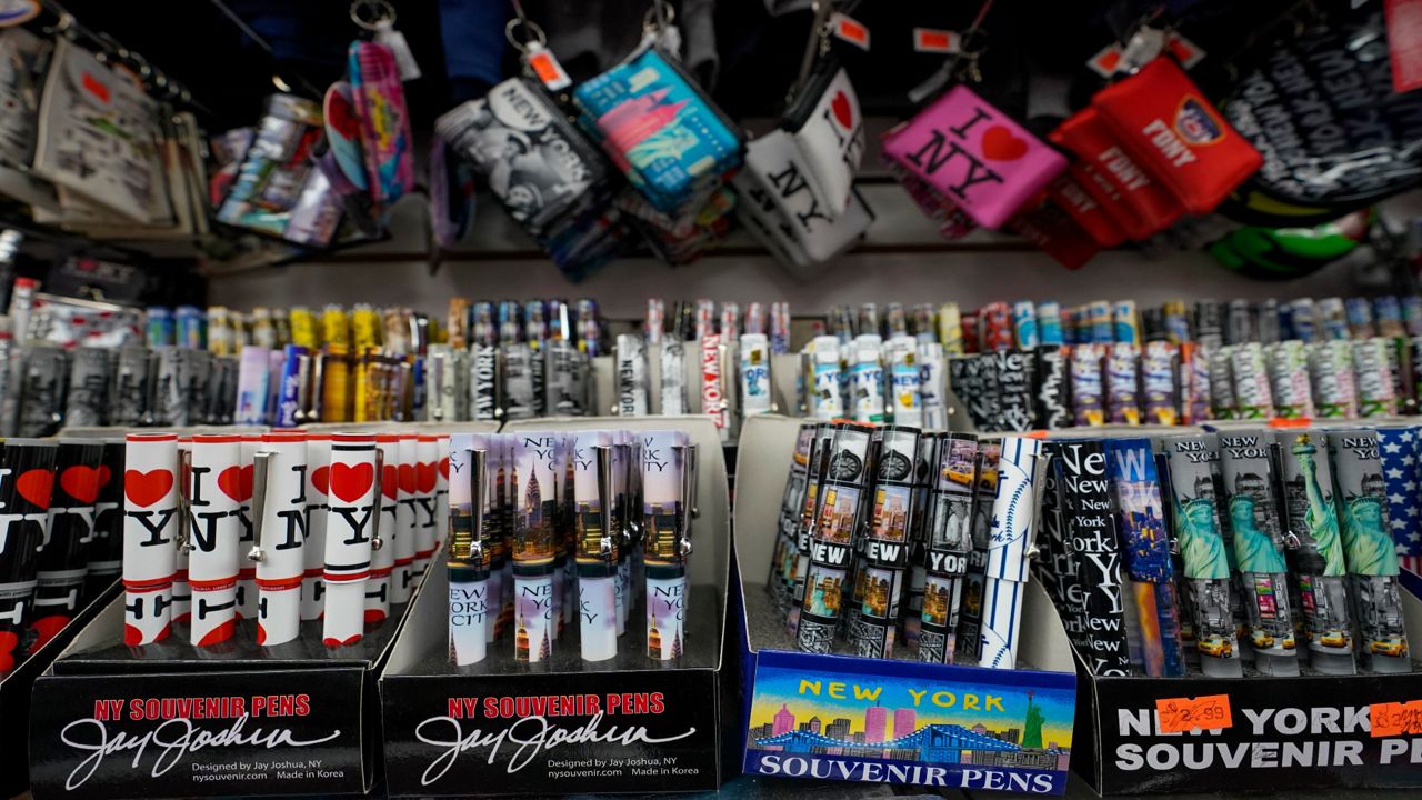 Souvenir pens and coin purses are on display for sale at a gift shop, Thursday, Nov. 12, 2020, in New York's Times Square. In souvenir shops from Times Square to the World Trade Center, shelves full of T-shirts and trinkets still love New York, as the slogan goes. But the proprietors wonder when their customers will, again. The coronavirus has altered many aspects of life and business in the United States' biggest city, and the pandemic is taking a major toll on the gifts-and-luggage stores that dot tourist-friendly areas. After setting records year after year since 2010, travel to New York has plummeted during the pandemic.