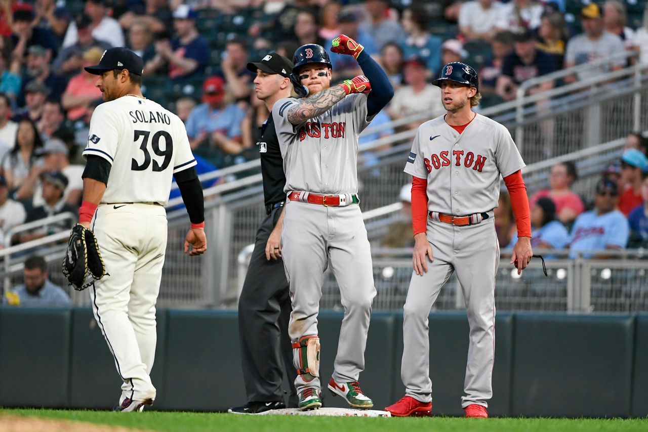 Boston Red Sox's Alex Verdugo, center, gestures after hitting an RBI single next to Minnesota Twins first baseman Donovan Solano (39) and  Red Sox first base coach Kyle Hudson during the eighth inning of a baseball game, Monday, June 19, 2023, in Minneapolis. (AP Photo/Craig Lassig)