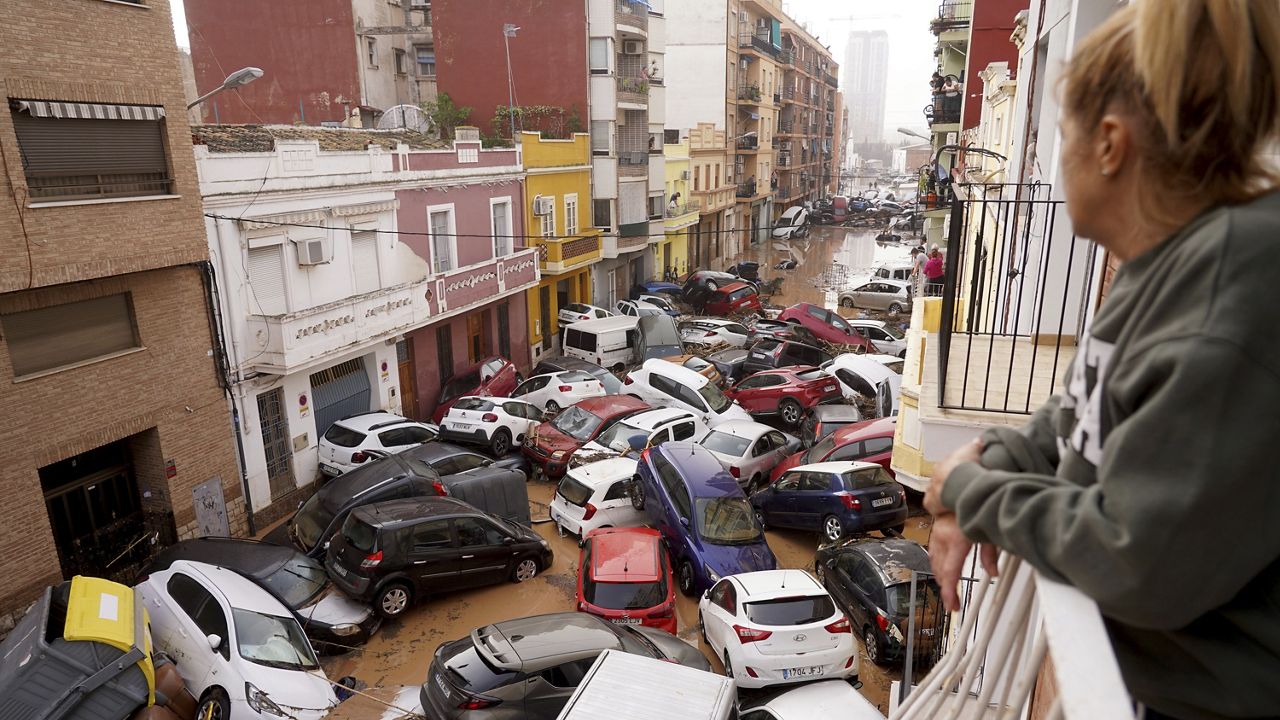 A woman looks out from her balcony as vehicles are trapped in the street during flooding in Valencia, Wednesday, Oct. 30, 2024. (AP Photo/Alberto Saiz)