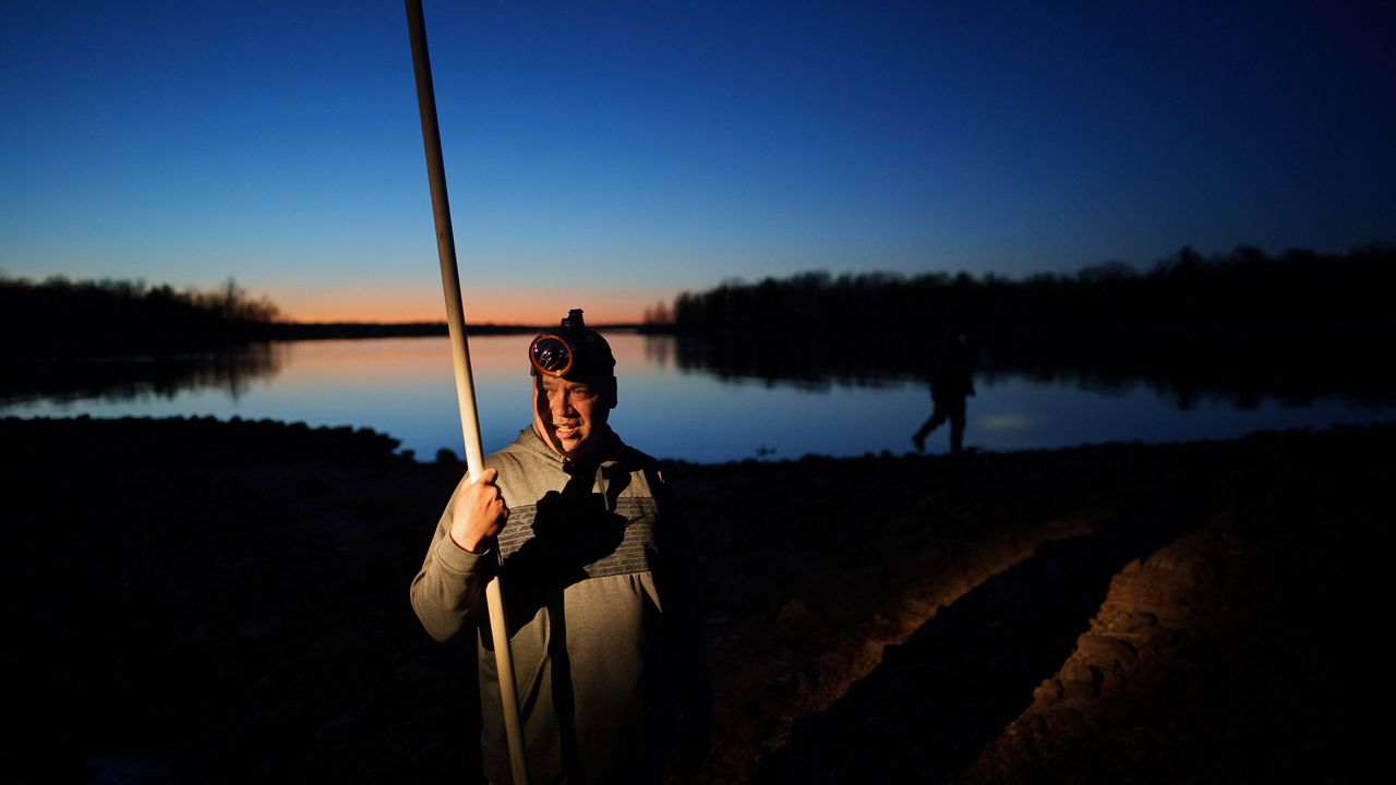 John Baker holds a spear while getting ready for a night of fishing