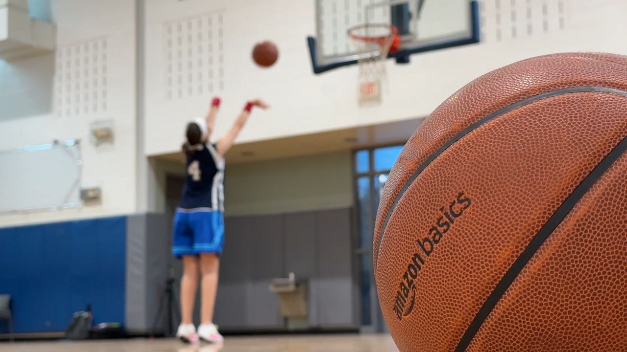 close up photo of a basketball with someone in the background shooting a ball into a hoop