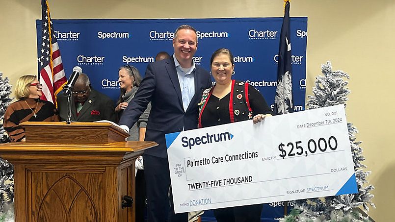 Christopher Bailey, senior director of government affairs for Spectrum Cable, awards a $25,000 check to Palmetto Care Connections to support its digital literacy program. (Spectrum News)