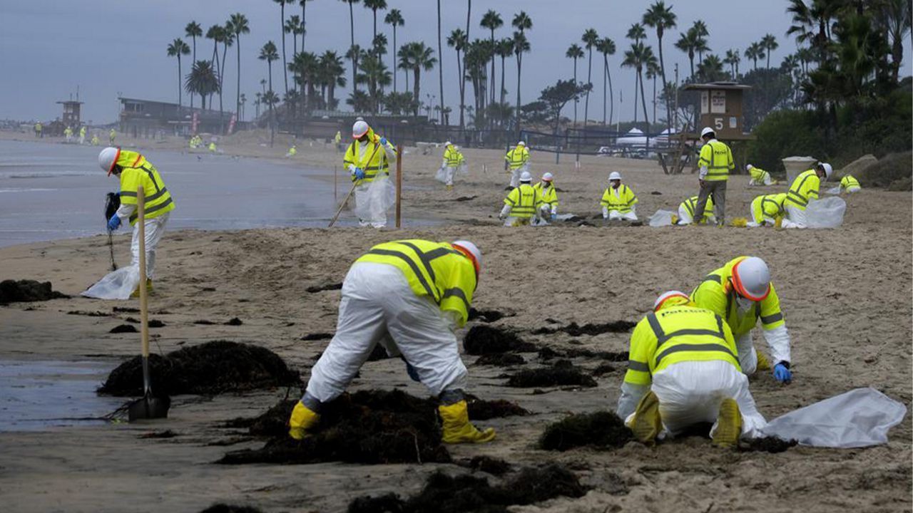 In this Oct. 7, 2021, file photo, workers in protective suits clean the contaminated beach in Corona Del Mar after an oil spill in Newport Beach, Calif. (AP Photo/Ringo H.W. Chiu, File)