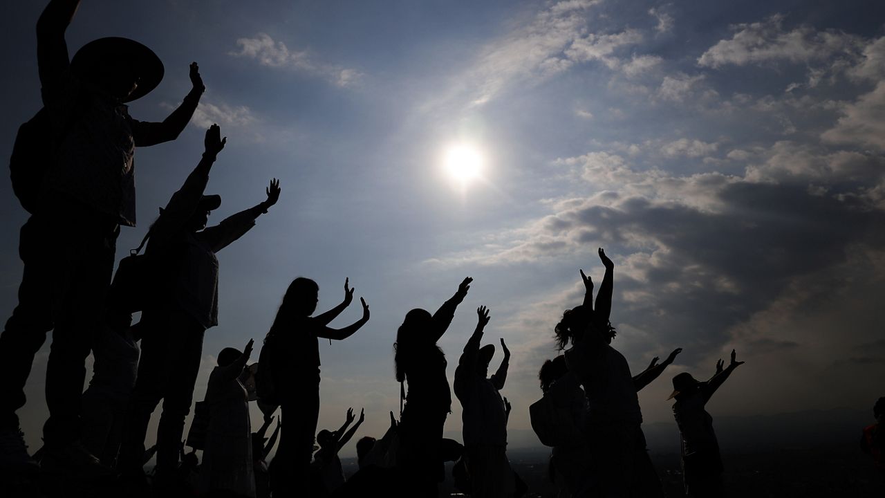 Visitors hold their hands out to receive the sun's energy as they celebrate the Spring equinox atop the Pyramid of the Sun in Teotihuacan, Mexico, Thursday, March 21, 2019. 