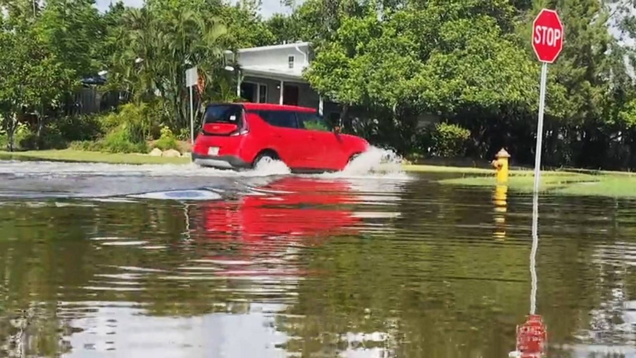 A car travels through a flooded neighborhood in St. Petersburg. (Spectrum News)