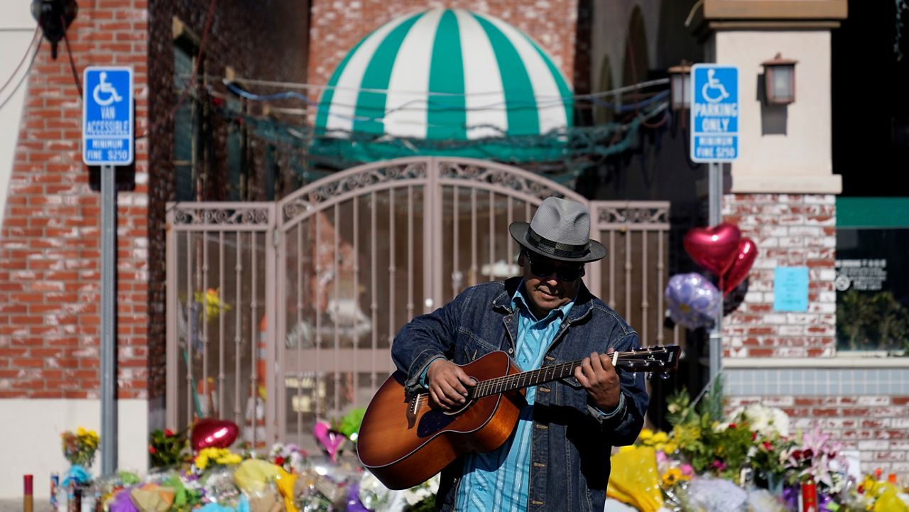 Gabriel Alexander plays a guitar and sings near a memorial outside the Star Ballroom Dance Studio on Tuesday, Jan. 24, 2023, in Monterey Park, Calif. (AP Photo/Ashley Landis)