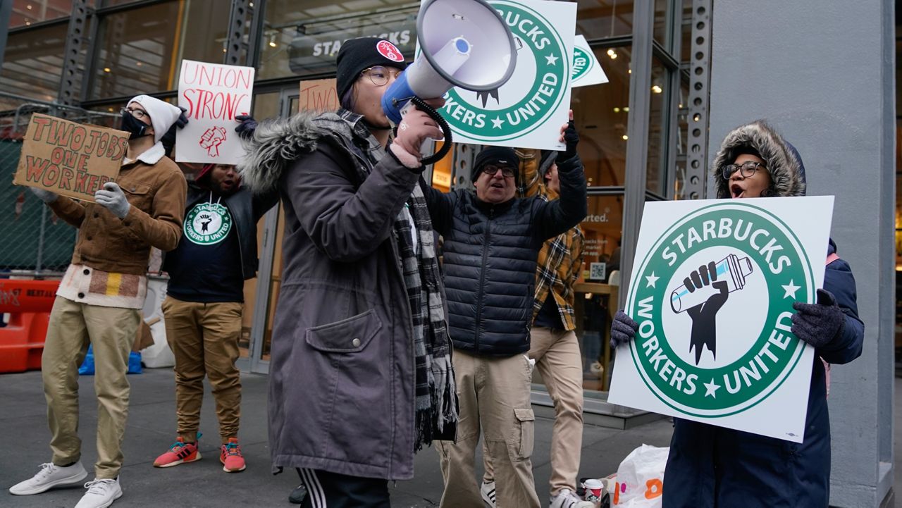 People chant and hold signs in front of a Starbucks in New York, Thursday, Nov. 17, 2022. (AP Photo/Seth Wenig)