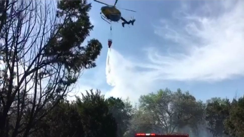 A STARflight helicopter drops water on a grass fire in Jonestown, Texas, in this image from April 17, 2018. (Travis County ESD 1)