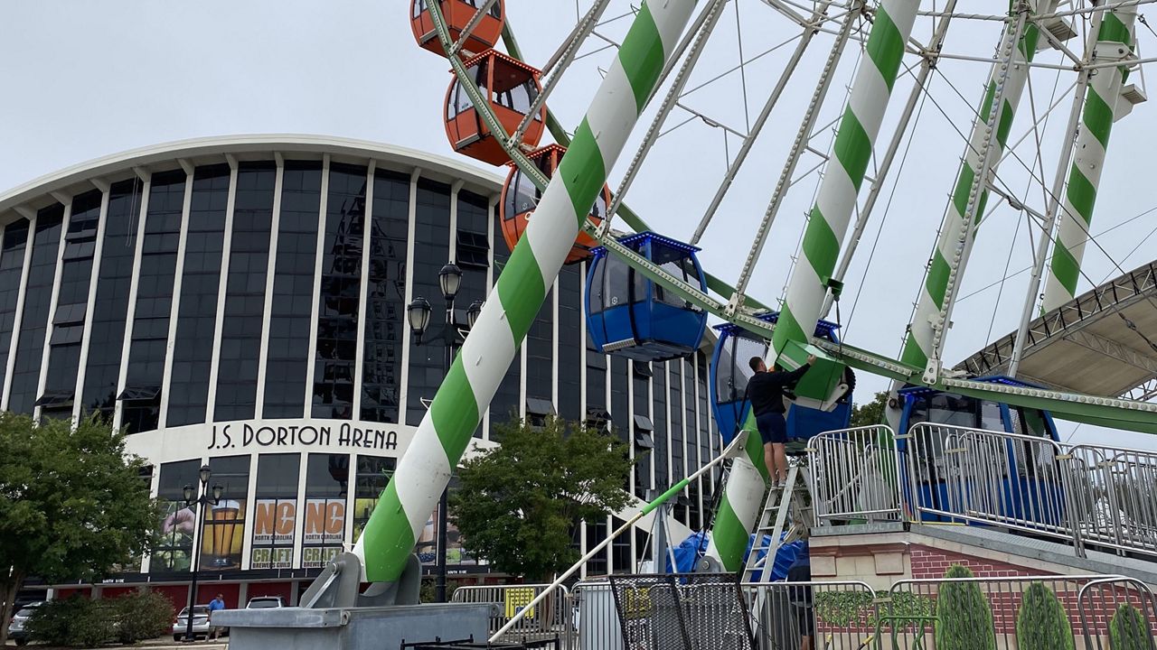 Workers clean the Ferris wheel set up along Hillsborough Street ahead of the N.C. State Fair. (Spectrum News 1/Charles Duncan)