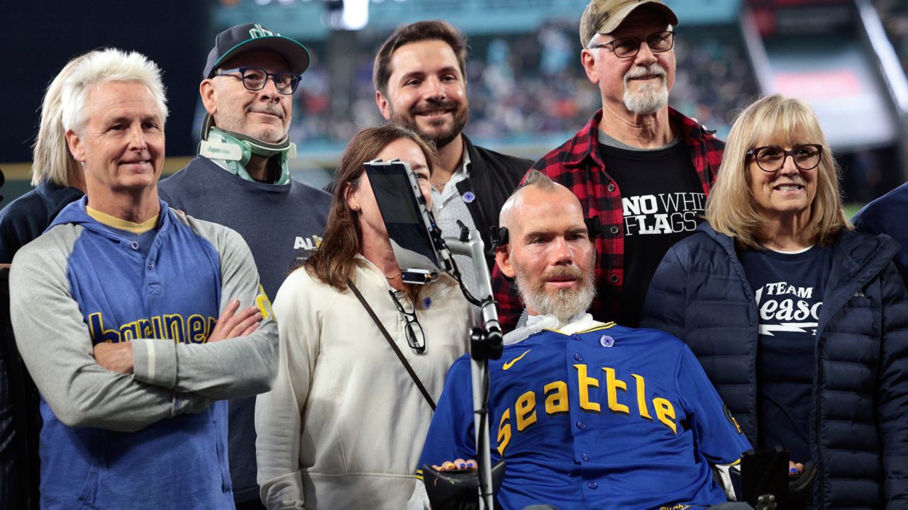 Former NFL football player and ALS patient Steve Gleason, second from right, and Pearl Jam guitarist Mike McCready, left, participate in ceremonies in commemoration of Lou Gehrig Day before a baseball game between the Mariners and the Los Angeles Angels, June 2, 2024, in Seattle. (AP Photo/Jason Redmond)