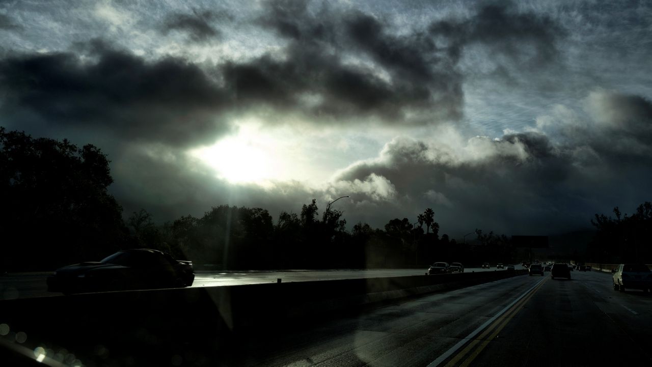 A glimmer of sunshine is seen as fast moving storm clouds pass over the Hollywood Freeway early Monday, Jan. 16, 2023, in Los Angeles.