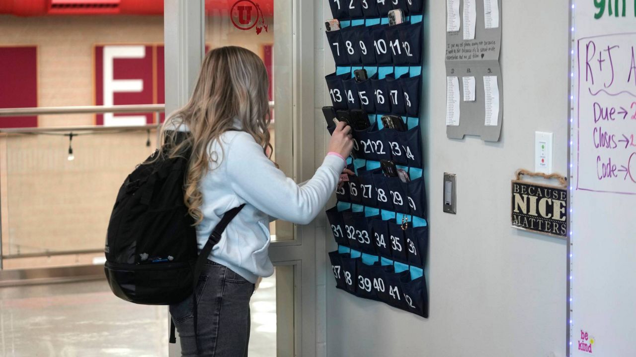 A ninth grader places her cellphone in to a phone holder as she enters class at Delta High School on Friday in Delta, Utah. (AP Photo/Rick Bowmer)