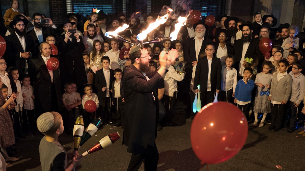 A performer wears lighted sticks on his head while entertaining a crowd during the the Jewish holiday of Sukkot on Tuesday, Oct. 18, 2016 in Brooklyn.