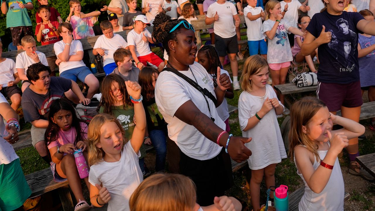 Counselor Kendra Ashong, center, sings a song with other campers, Thursday, June 20, 2024, at YMCA Camp Kern in Oregonia, Ohio.As the first heat wave of the season ripples across the U.S., summer camps are working to keep their children cool while still letting the kids enjoy being outside with nature. (AP Photo/Joshua A. Bickel)