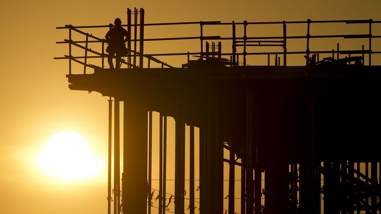 Construction workers start their day as the sun rises on the new Republic Airlines headquarters building in Carmel, Ind., Tuesday, Aug. 27, 2024. (AP Photo/Michael Conroy)