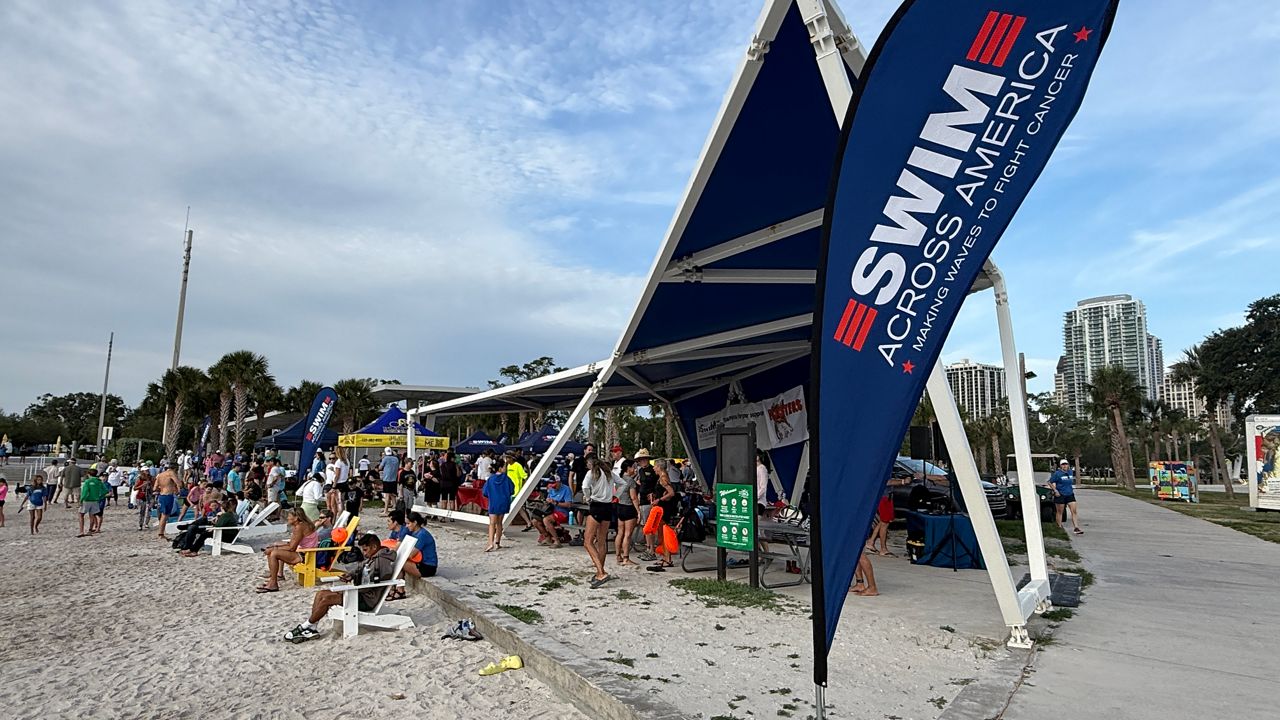 Spectators sit on the beach during Saturday's Swim Across America that benefits cancer research. (Spectrum News)