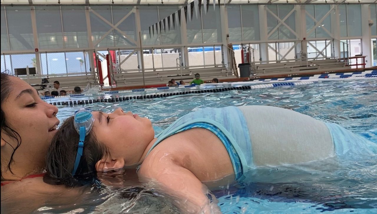 Diana Balderas teaches a child how to control her breathing to float effortlessly. (photo credit: Adolfo Muniz/Spectrum News 1)