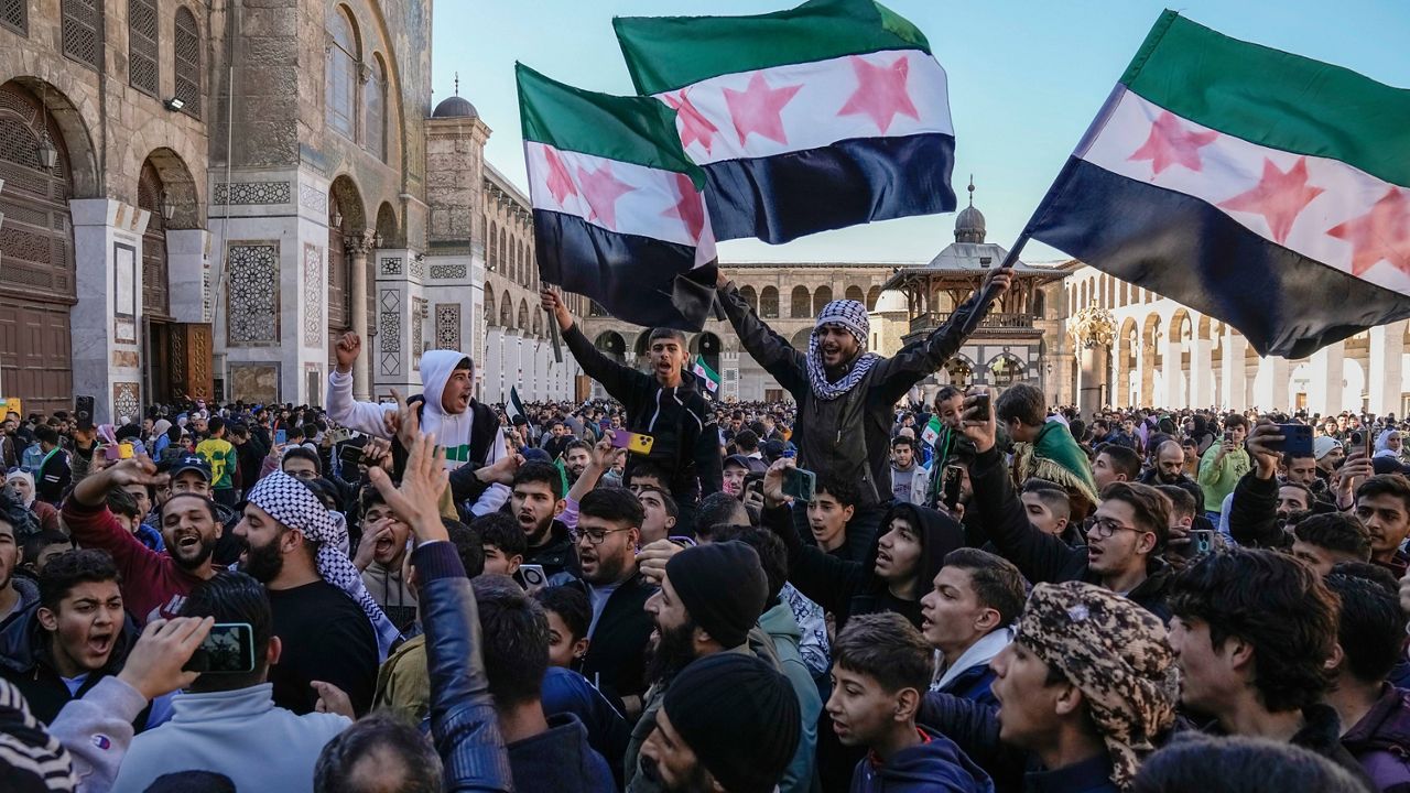 Syrians chant slogans and wave the new Syrian flag as they gather for Friday prayers at the Umayyad mosque in Damascus, Syria, Friday, Dec. 13, 2024. (AP Photo/Leo Correa)