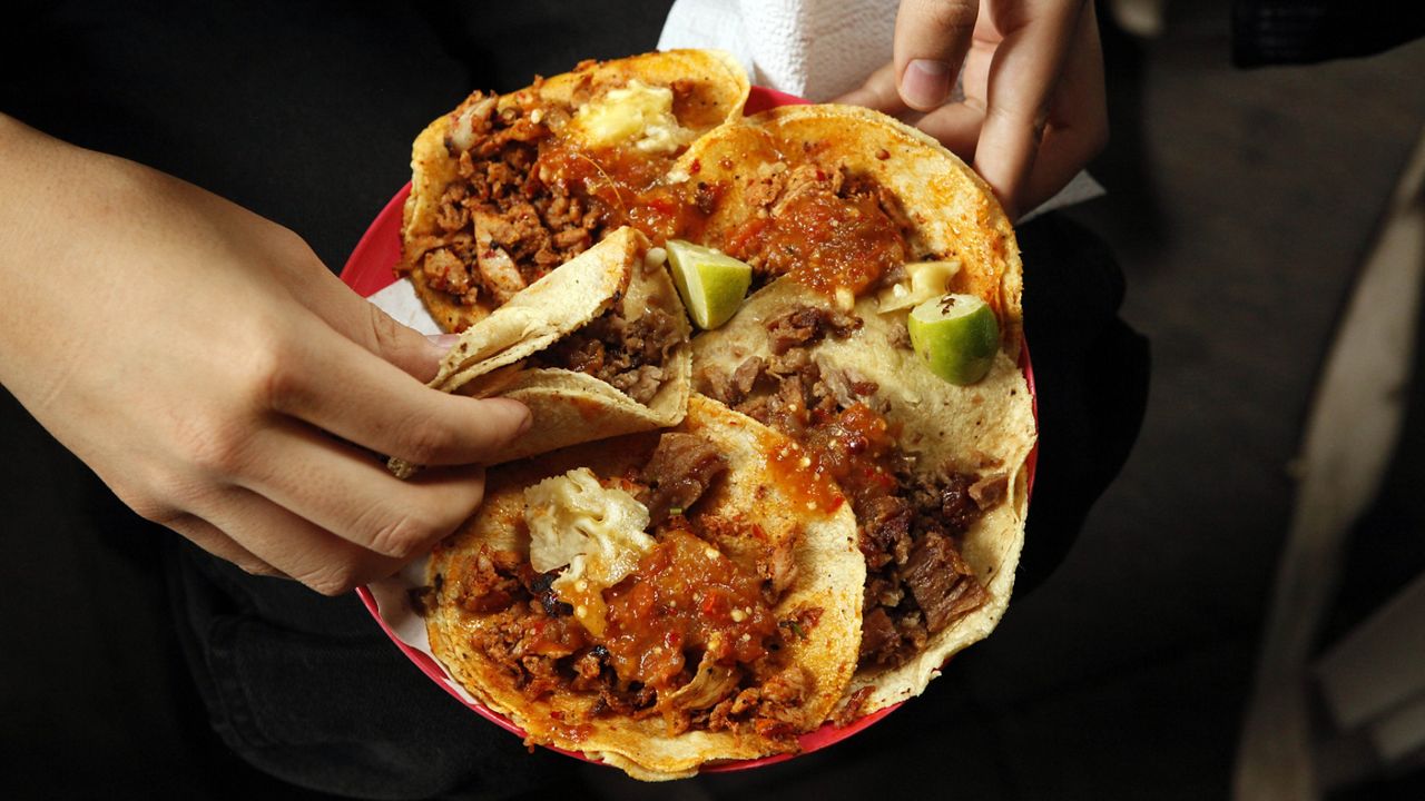 A woman holds a plate that include tacos al pastor and alambre at the inauguration of the Tlalpan Taco Fair featuring 20 different tacos, in Mexico City, Saturday, June 15, 2013. (AP Photo/Ivan Pierre Aguirre)(AP Photo/Ivan Pierre Aguirre)