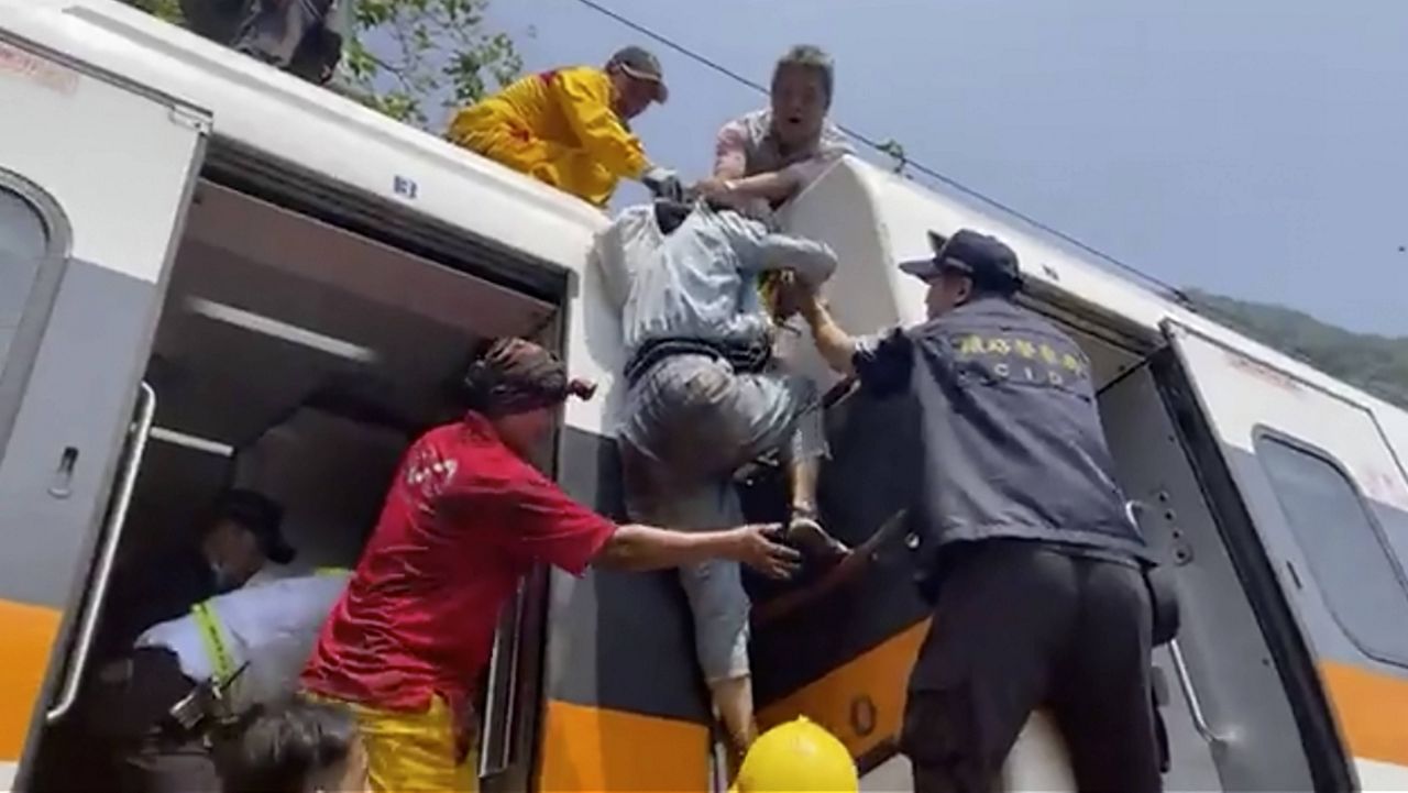In this image made from a video released by hsnews.com.tw, a passenger is helped to climb out of a derailed train in Hualien County in eastern Taiwan on Friday. (hsnews.com.tw via AP)