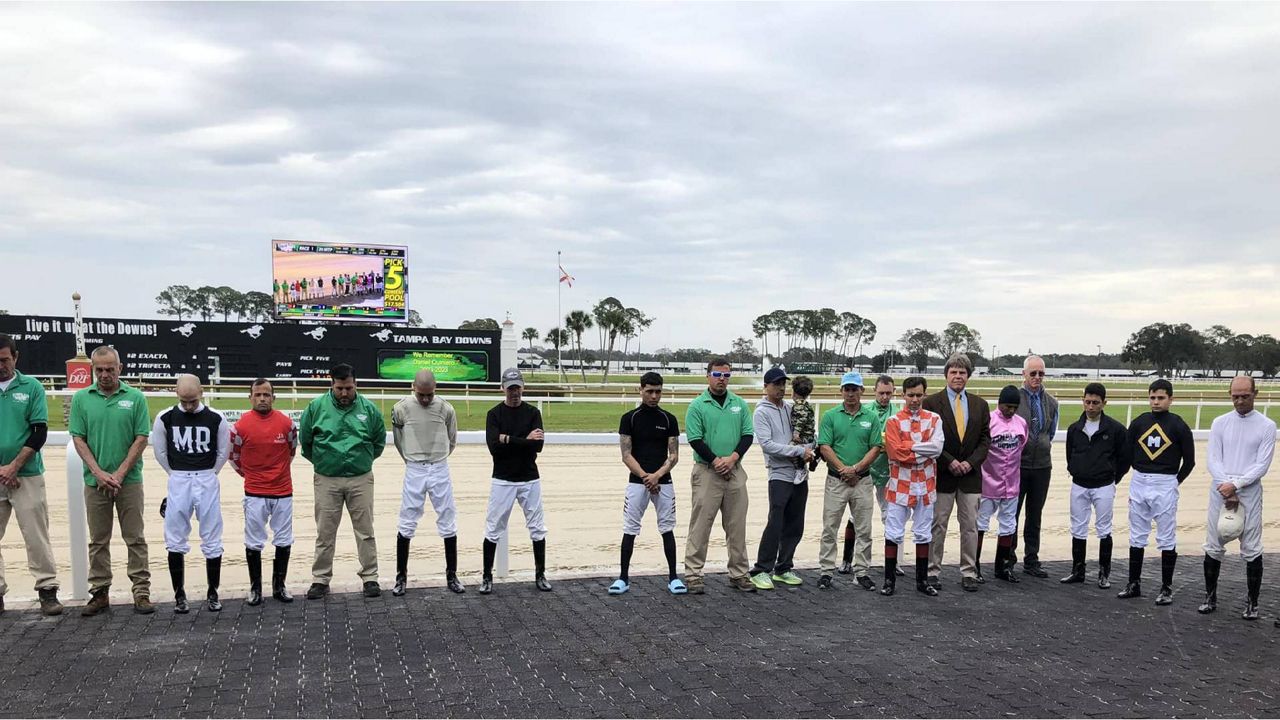 Jockeys and their valets observe a moment of silence in honor of 19-year-old exercise rider Daniel Quintero, who died Saturday morning in a training accident. (Photo: Tampa Bay Downs)