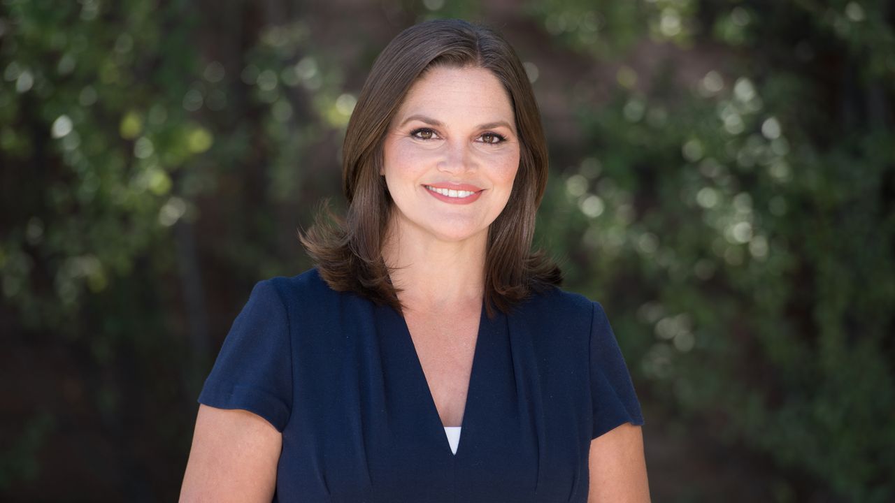 Photo of Tara Lynn Wagner standing in front of a background of greenery.