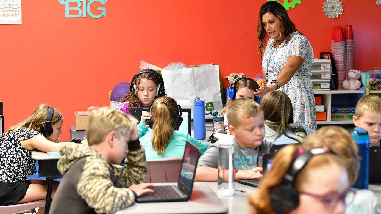 A teacher watches fourth grade students at Lakewood Elementary School in Cecilia, Ky., as they use their laptops to participate in an emotional check-in at the start of the school day, Thursday, Aug. 11, 2022. (AP Photo/Timothy D. Easley)