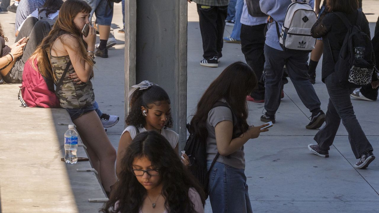 Students use their cellphones as they leave for the day at Ramon C. Cortines School of Visual and Performing Arts High School in downtown Los Angeles, Aug. 13, 2024. (AP Photo/Damian Dovarganes, File)