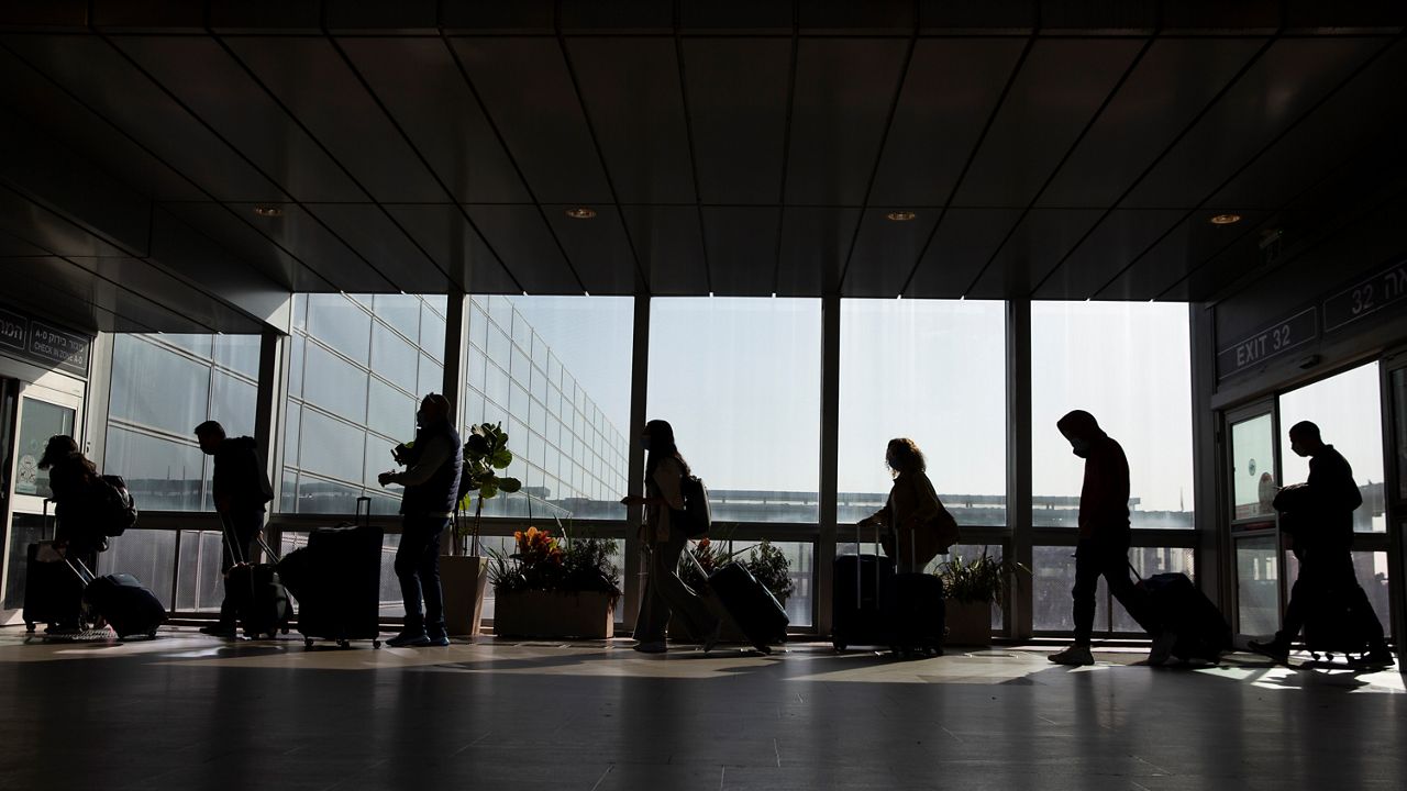 Travelers walk with their luggage in the Ben Gurion Airport near Tel Aviv, Israel, Sunday, Nov. 28, 2021. (AP Photo/Ariel Schalit)