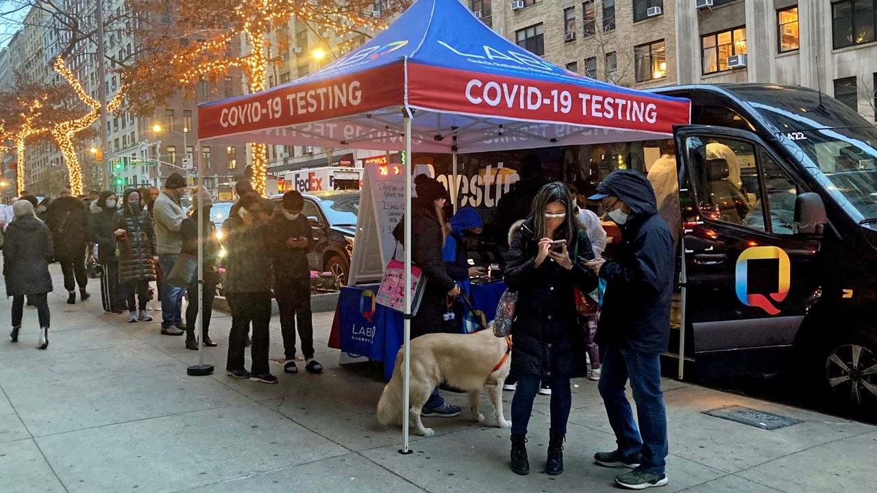 People line up for PCR and Rapid Antigen COVID-19 coronavirus tests on Wall Street in the Financial District, Thursday, Dec. 16, 2021. (AP Photo/Ted Shaffrey)