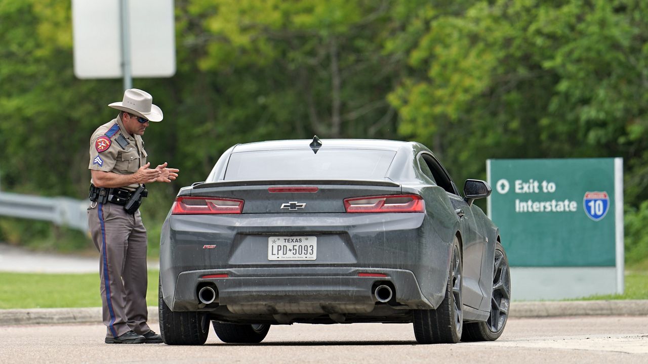 A Texas Department of Public Safety State Trooper talks with a driver at a rest stop along Interstate, 10 Monday, March 30, 2020, in Orange, Texas, near the Louisiana state border. (AP Photo/David J. Phillip)
