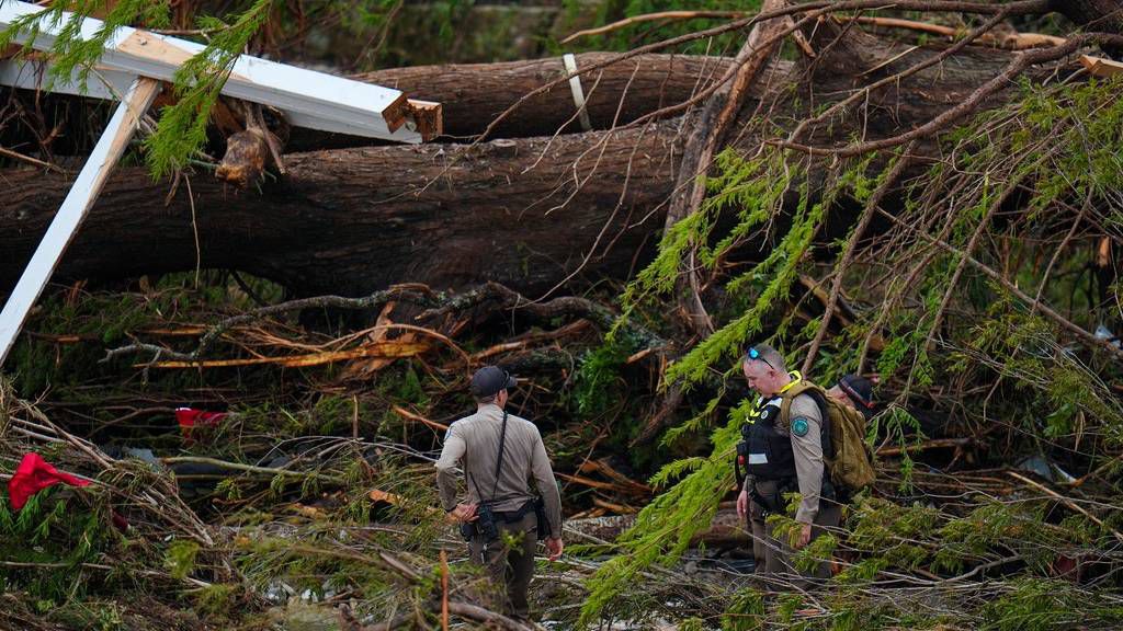 Officials with the Texas Game Warden comb through debris along the banks of the Guadalupe River after a flash flood swept through the area Saturday, July 5, 2025, in Hunt, Texas. (AP Photo/Julio Cortez)