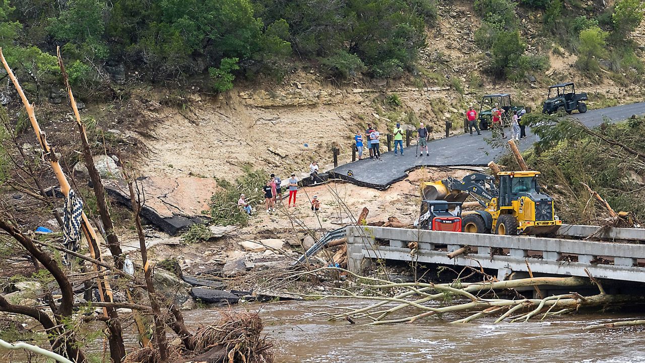 Crews work to clear debris from the Cade Loop bridge along the Guadalupe River on Saturday, July 5, 2025, in Ingram, Texas. (AP Photo/Rodolfo Gonzalez)